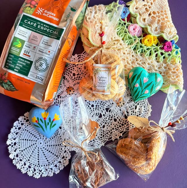 Biscoitos embalados com barbante, corações pintados à mão e peças de crochê sobre fundo roxo