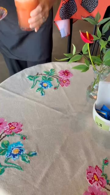 Toalha de mesa com bordado de flores coloridas e vaso com antúrio