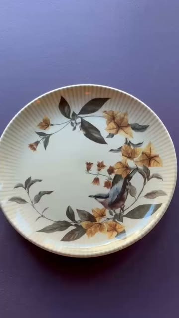 Prato de porcelana com pássaro e flores amarelas sobre fundo roxo