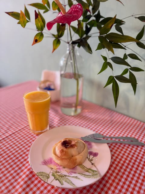 Empanada em prato florido ao lado de suco de laranja, toalha xadrez vermelha